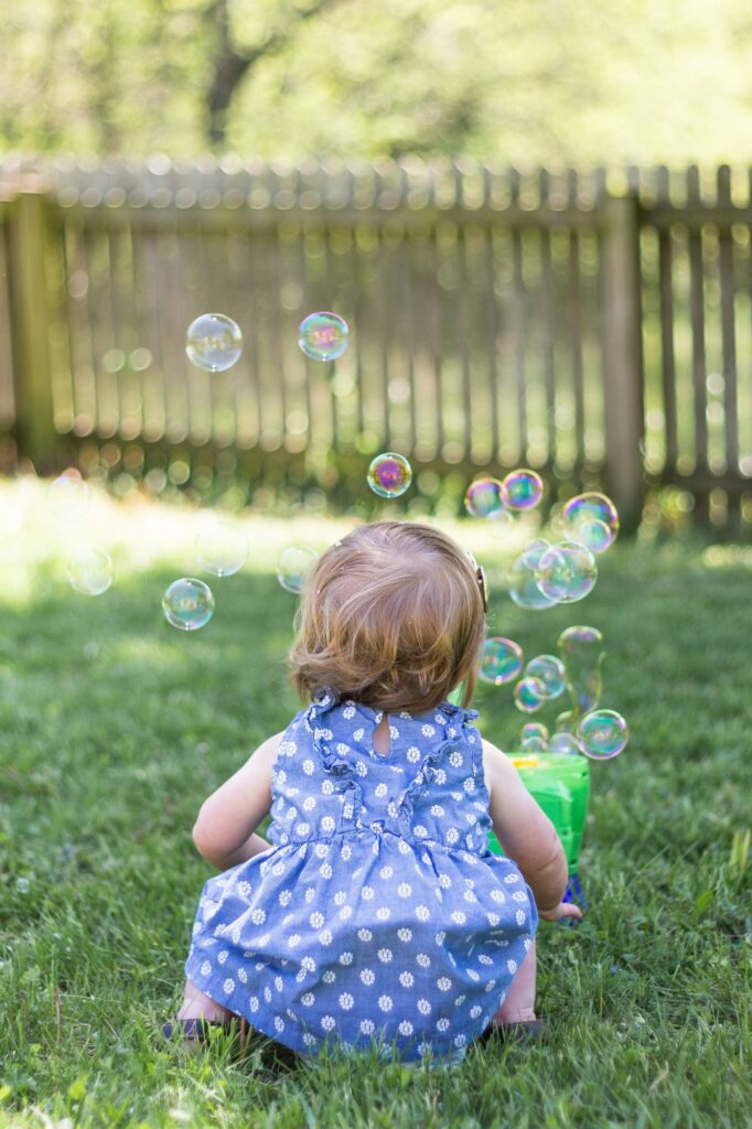Little girl having fun playing with bubbles in a backyard